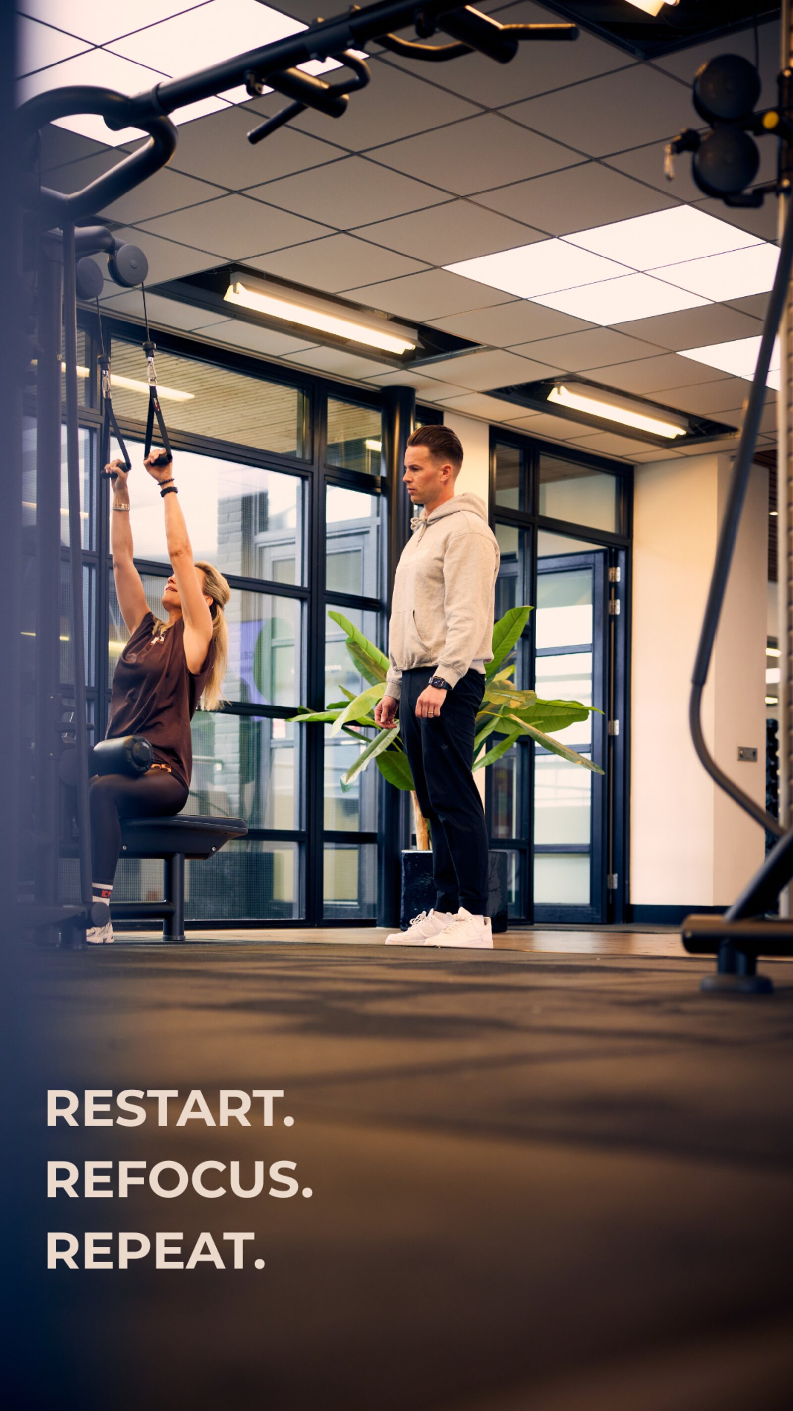 Trainer van L'Humain begeleidt een cliënt in de sportschool — restart, refocus, repeat